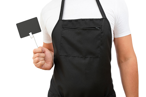 Torso of a male cook in a black apron with a price tag in his hand on a white background.
