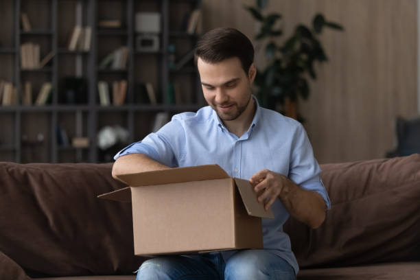 istock Interested young man unpacking big carton box, 1425167341