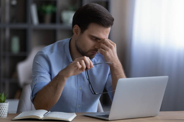 istock Stressed young male employee taking off eyeglasses. 1425167390