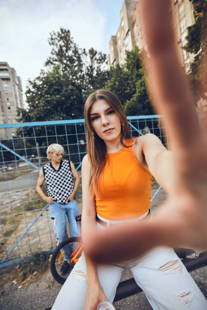 A teenage girl is catching camera while the boy in the background watching her. A teenage girl is catching camera while the boy in the background watching her. broad catch stock pictures, royalty-free photos & images