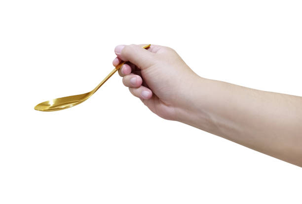 istock Hand holding Gold plated golden spoon isolated on white background 1425171546
