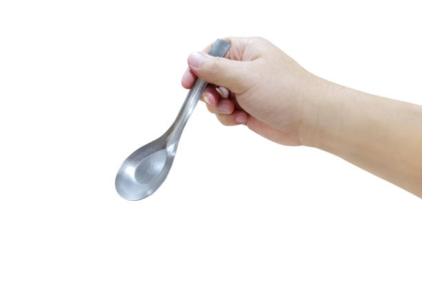 istock Hand holding a silver plated spoon isolated on white background. 1425171553