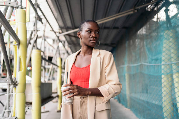 istock Stylish young woman standing under scaffolding in a construction site 1425172021