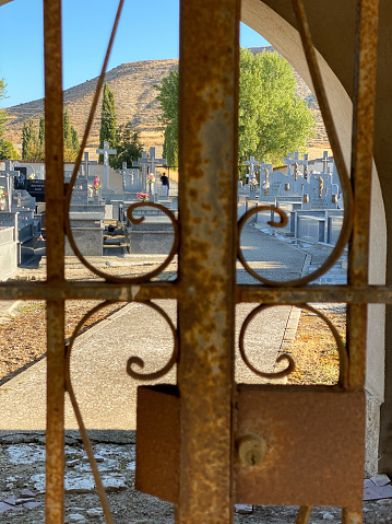 Closed iron gate overlooking a rural cemetery