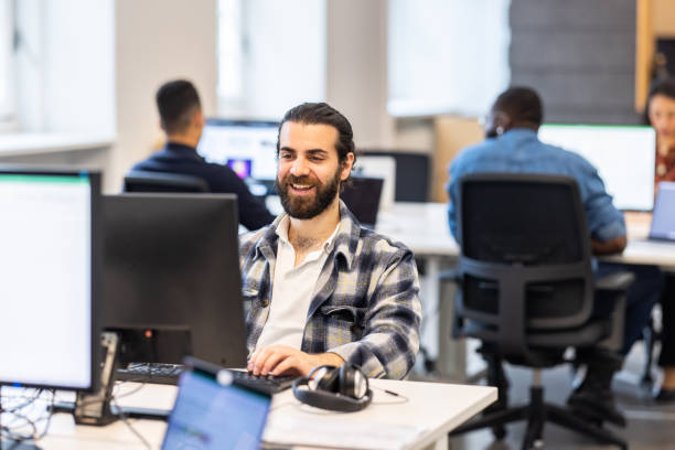 istock Smiling young man working on a computer at a coworking office 1425175197