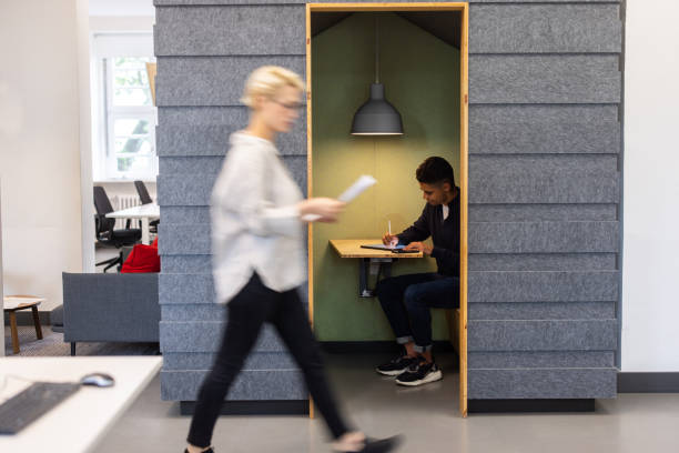 Two businesspeople engage in a meeting at a contemporary office. One individual checks a mobile device while another uses a tablet, showcasing teamwork in a vibrant environment.