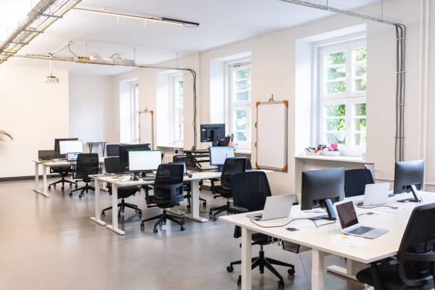 Modern empty open plan office interior Interior of a coworking office space with computers and laptops in desks. Modern open plan office with no people. small office stock pictures, royalty-free photos & images