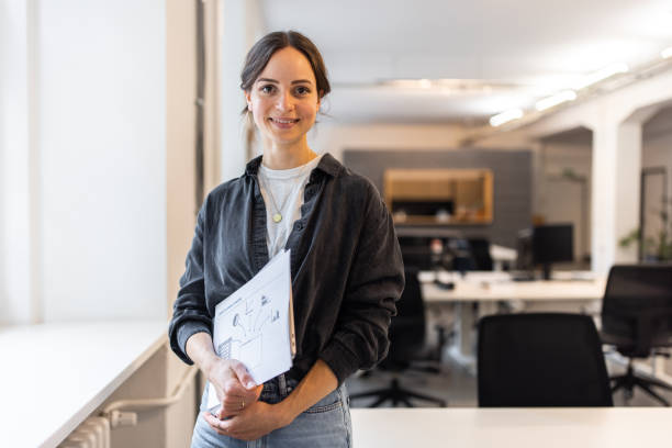 istock Confident young woman standing in office 1425175485