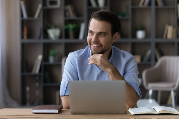 istock Distracted from computer work young businessman looking in distance. 1425175795