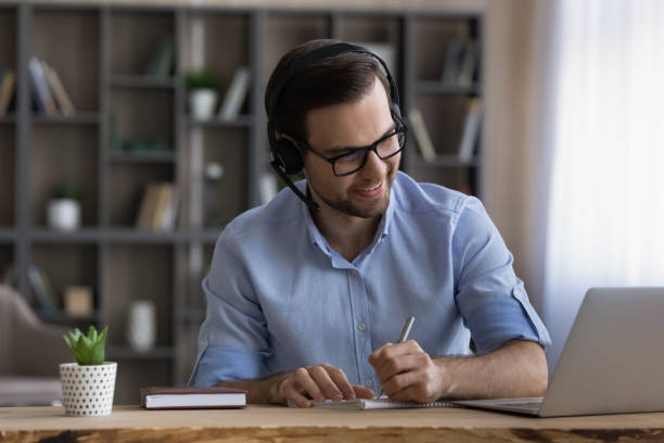 istock Smiling millennial man in headset holding video call meeting. 1425175800