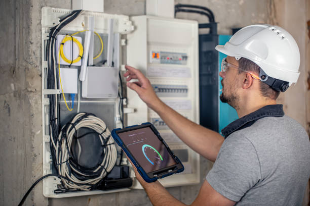 istock Man, an electrical technician working in a switchboard with fuses, uses a tablet. 1425179216