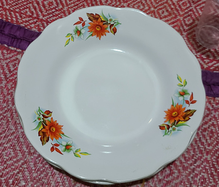 High angle view of an empty round plate with flower design indeed.