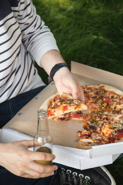 istock A young man eating pizza on a picnic. 1425180025
