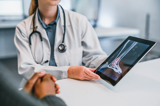 Doctor consulting patient on ankle xray results to help give professional medical advice on leg, foot and joint accident. Healthcare worker in x ray consultation in emergency hospital using a tablet