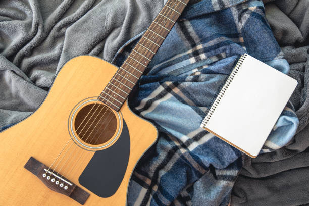 istock Acoustic guitar and notepad on a plaid background, top view. 1425180669