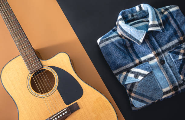istock Acoustic guitar and plaid shirt on a colored background, flat lay. 1425180680