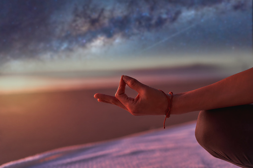 view of hand in meditation or yoga mudra position outdoors on the beach  at night