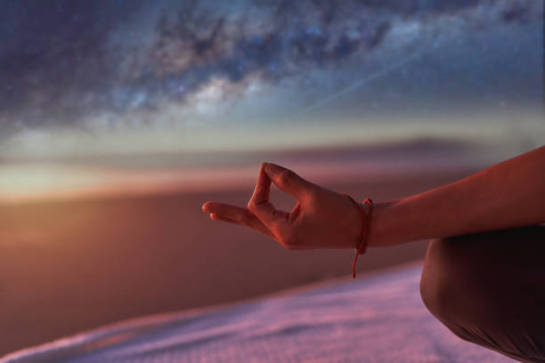view of hand in meditation or yoga mudra position outdoors on the beach  at night stock photo