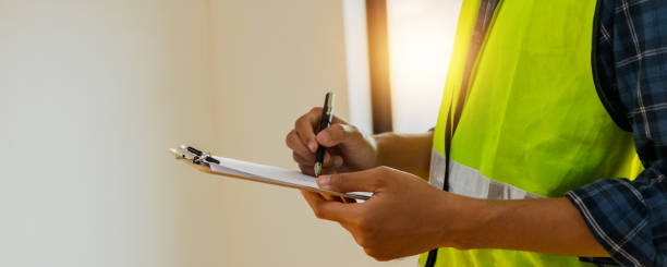 close up hands of inspector wear safety vest and checking list into clipboard, Architect Checking Insulation During House Construction stock photo