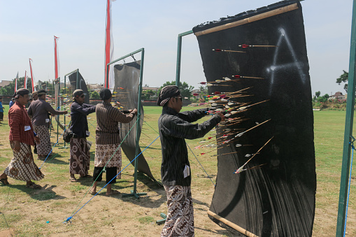 Yogyakarta, Indonesia - October 27, 2019: Jemparingan, a traditional archery sport from Java, Indonesia. Archers wear traditional Batik clothes and sit cross-legged while shooting