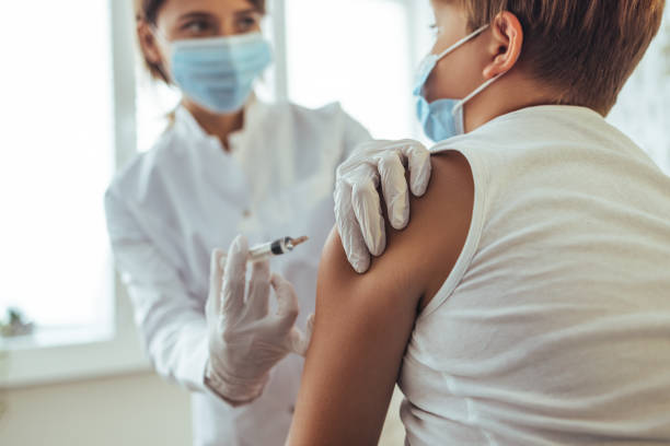 istock Boy in face mask getting flu shot at doctor's office during World Immunization Week 1425190630