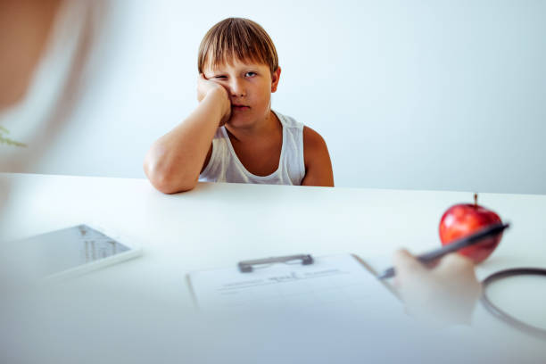 female nurse sitting next to a teenager patient explaining healthy eating habits - child obesity imagens e fotografias de stock