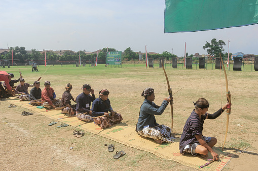 Yogyakarta, Indonesia - October 27, 2019: Jemparingan, a traditional archery sport from Java, Indonesia. Archers wear traditional Batik clothes and sit cross-legged while shooting