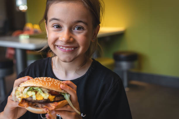 istock A little girl eats an appetizing burger, close-up. 1425194065