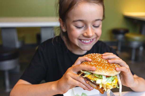 istock A little girl eats an appetizing burger, close-up. 1425194072