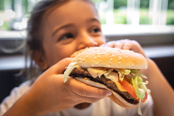 istock A little girl eats an appetizing burger, close-up. 1425194076