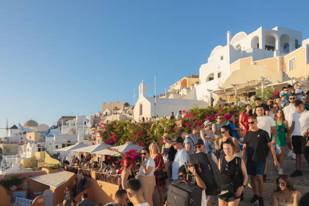 Oia, Greece - September 11, 2022: Narrow, overcrowded and cogested streets in Oia, Santorini filled with a crowd of tourists during summer high season in the Greek Islands.
