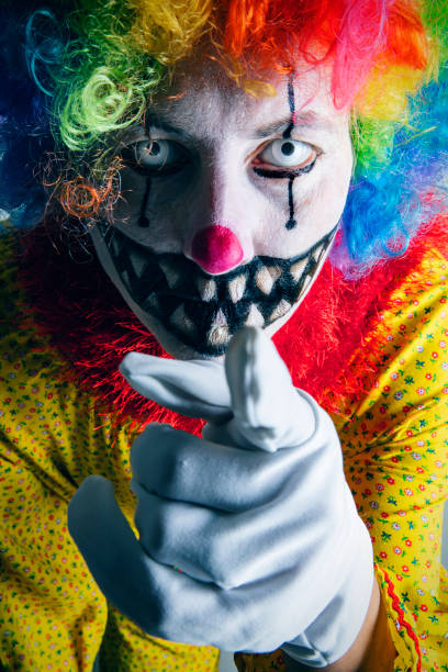 A creepy clown super close up pointing it's finger.