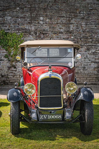 Beautiful wooden steering wheel and and old-fashioned small gauges and large beautiful exterior mirror of a historic cabriolet - right-hand drive