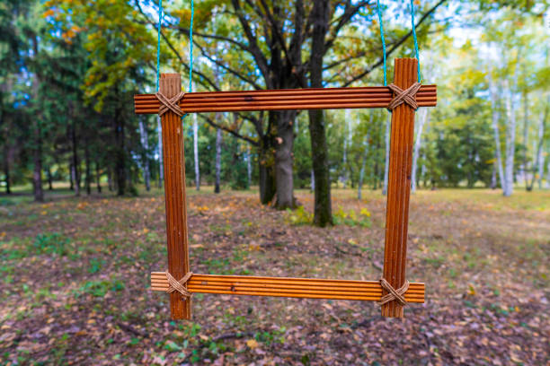 Early autumn. Deciduous forest. A wooden frame hangs on a tree branch. Nobody. Close-up