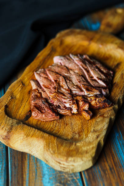 istock Sliced grilled steak medium rare served on wooden cutting board with vegetables 1425203732