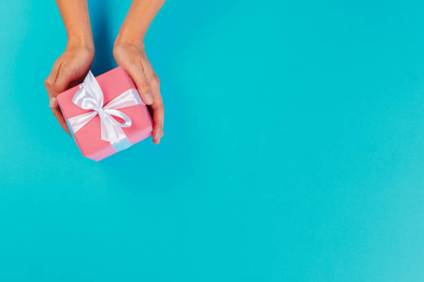istock Woman holding gift box on color background 1425203789