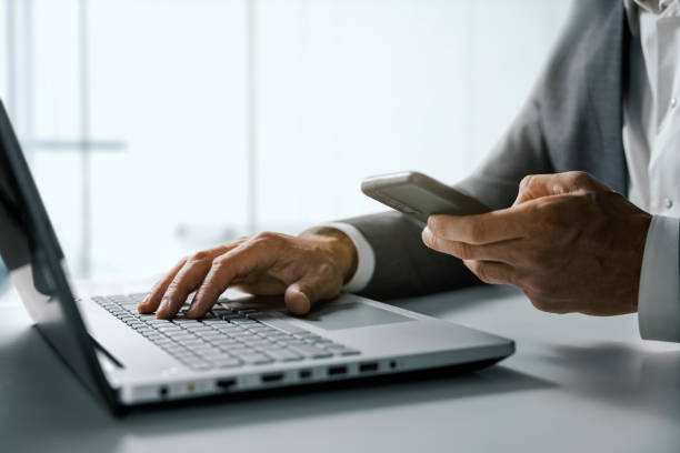 istock businessman using smart phone and working on laptop computer in office. business management and digital solutions concept 1425203845