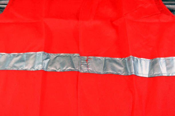 istock Red reflective safety vest with reflective stripes isolated on wooden background, light jacket vest for construction works, drivers, road workers and firefighters with fluorescent protective stripe 1425206432