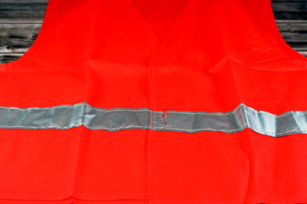 gilet de sécurité réfléchissant rouge avec bandes réfléchissantes isolées sur fond en bois, gilet veste légère pour les travaux de construction, les conducteurs, les travailleurs de la route et les pompiers avec bande de protection fluorescente - red vest photos et images de collection