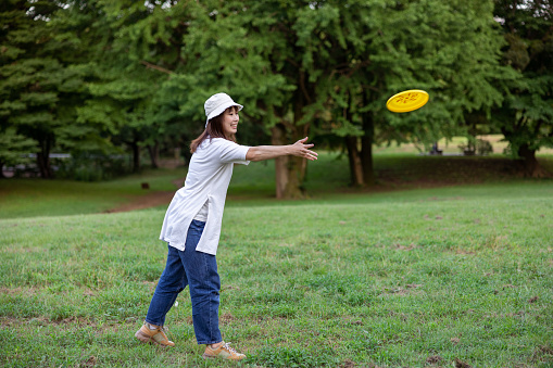 Japanese family visiting public park by bicycle to enjoy walking in forest, playing with ball and equipments, eating foods.