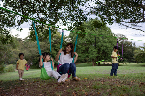 Little girl in a swing being push by her friend