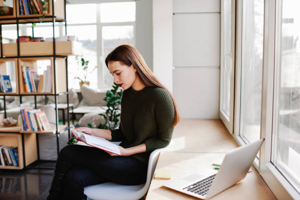 istock Serious woman reading notebook in library 1425206703