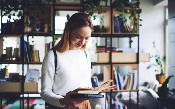 istock Happy teen standing in bookstore with open book 1425206730