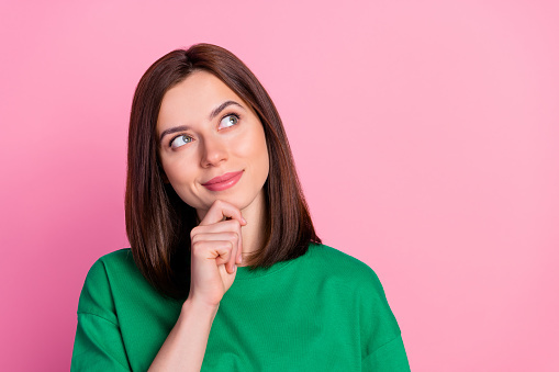 Photo of young funny attractive woman touch chin interested hmm looking empty space isolated on pink color background.