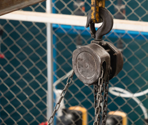 Close up picture of steel hoist and brown chain used to help lift heavy objects to heights for industrial use, safety stock photo