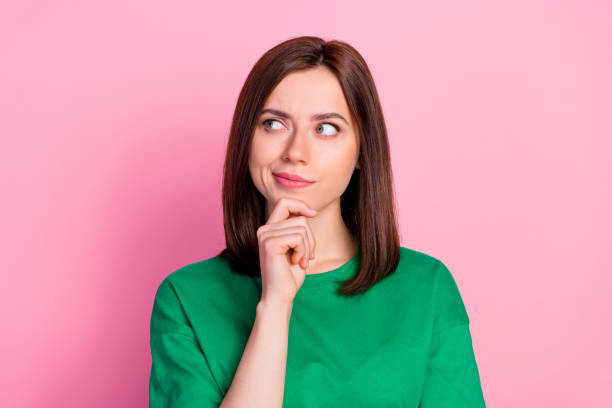 ritratto fotografico di bella giovane donna scettica sguardo spazio vuoto non credere dubbio vestito alla moda verde aspetto isolato su sfondo di colore rosa - uncertainty foto e immagini stock