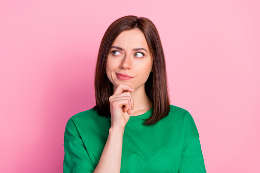 Photo portrait of nice young lady skeptical look empty space not believe doubt dressed trendy green look isolated on pink color background.