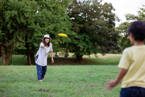 istock Mother throwing flying disc to her son in public park 1425209615