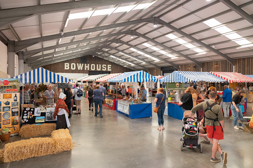 East Neuk, UK - August 14, 2022: Shoppers visit market stalls inside a barn at the rural country Bowhouse Farmer's Market at East Neuk in Fife, Scotland.