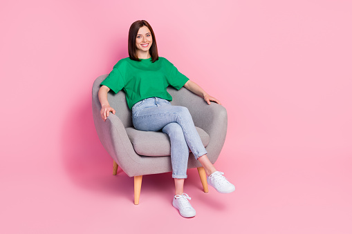 Full size portrait of gorgeous satisfied girl sitting comfy chair toothy smile isolated on pink color background.